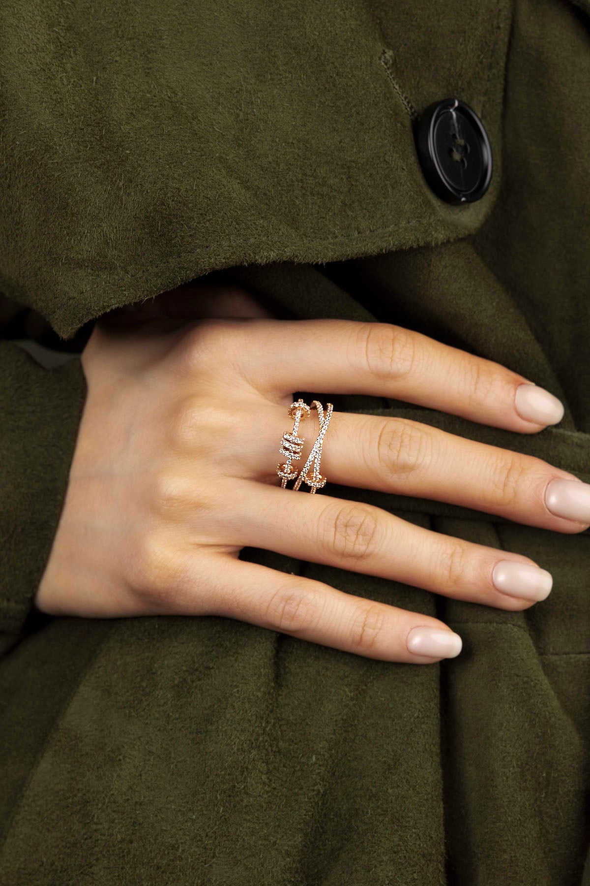 Hand wearing a ring on an olive green coat