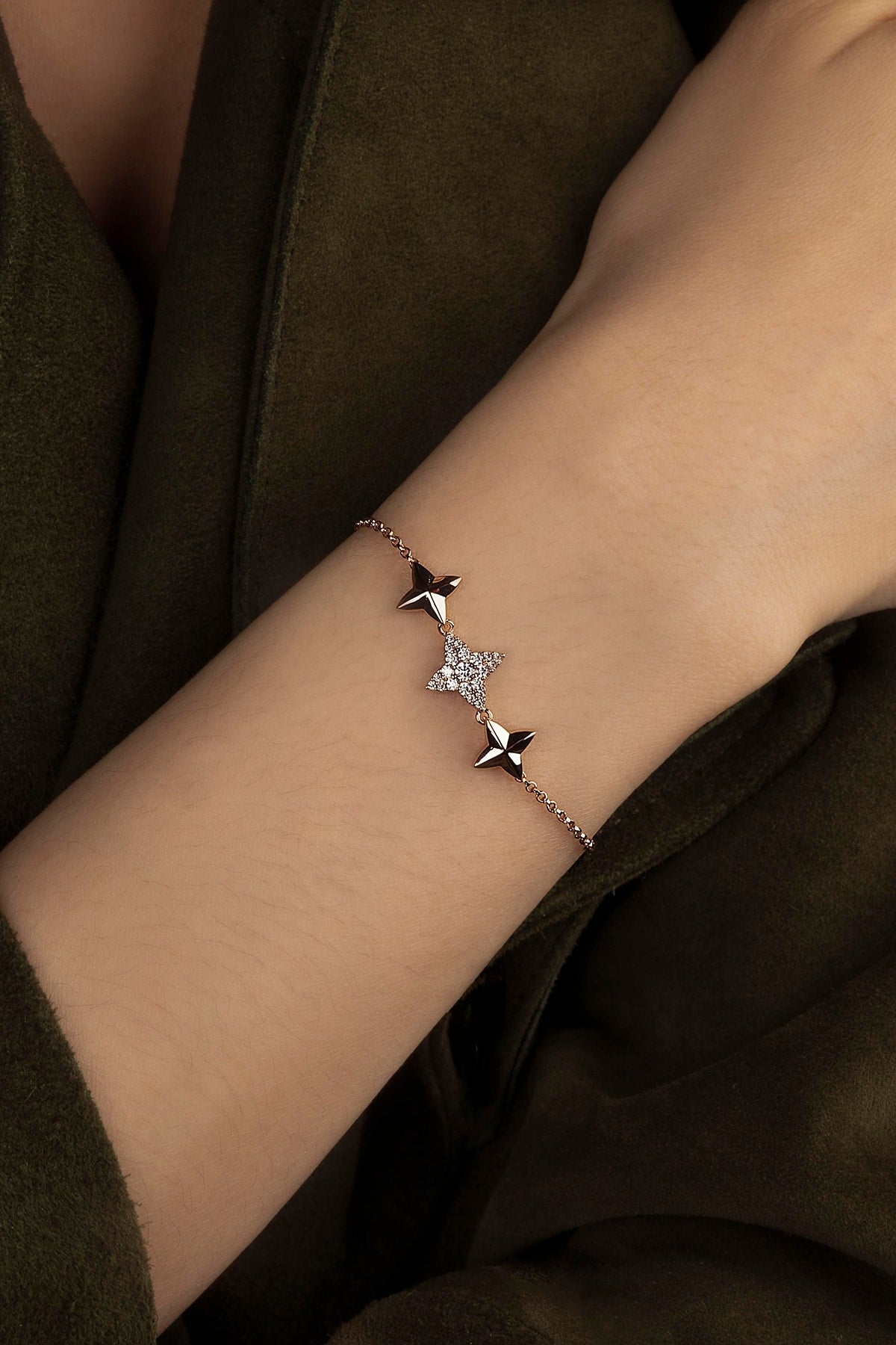 Bracelet with star-shaped charms on a wrist against a dark background