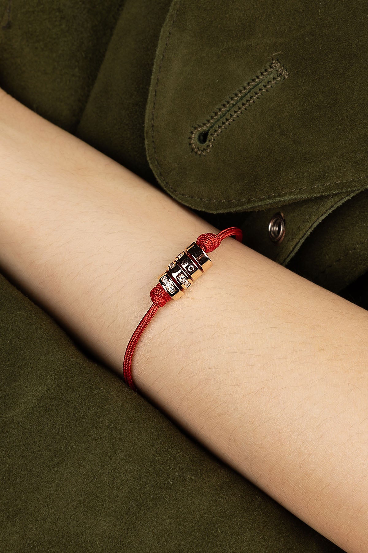 Red bracelet on a wrist with a green jacket background