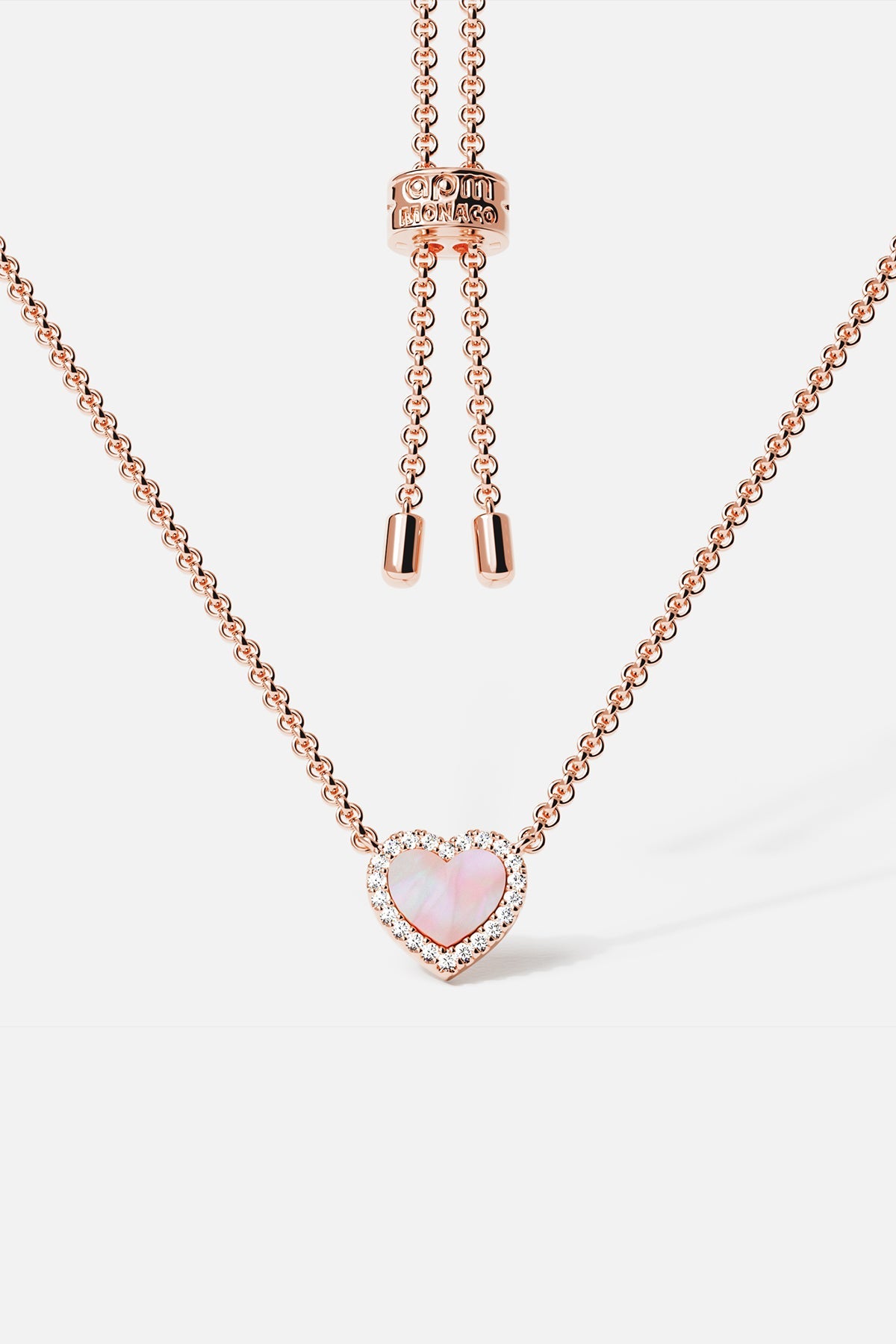 Necklaces APM Monaco, rose gold tone adjustable chain with a pink nacre (mother-of-pearl) heart pendant surrounded by crystal pavé.