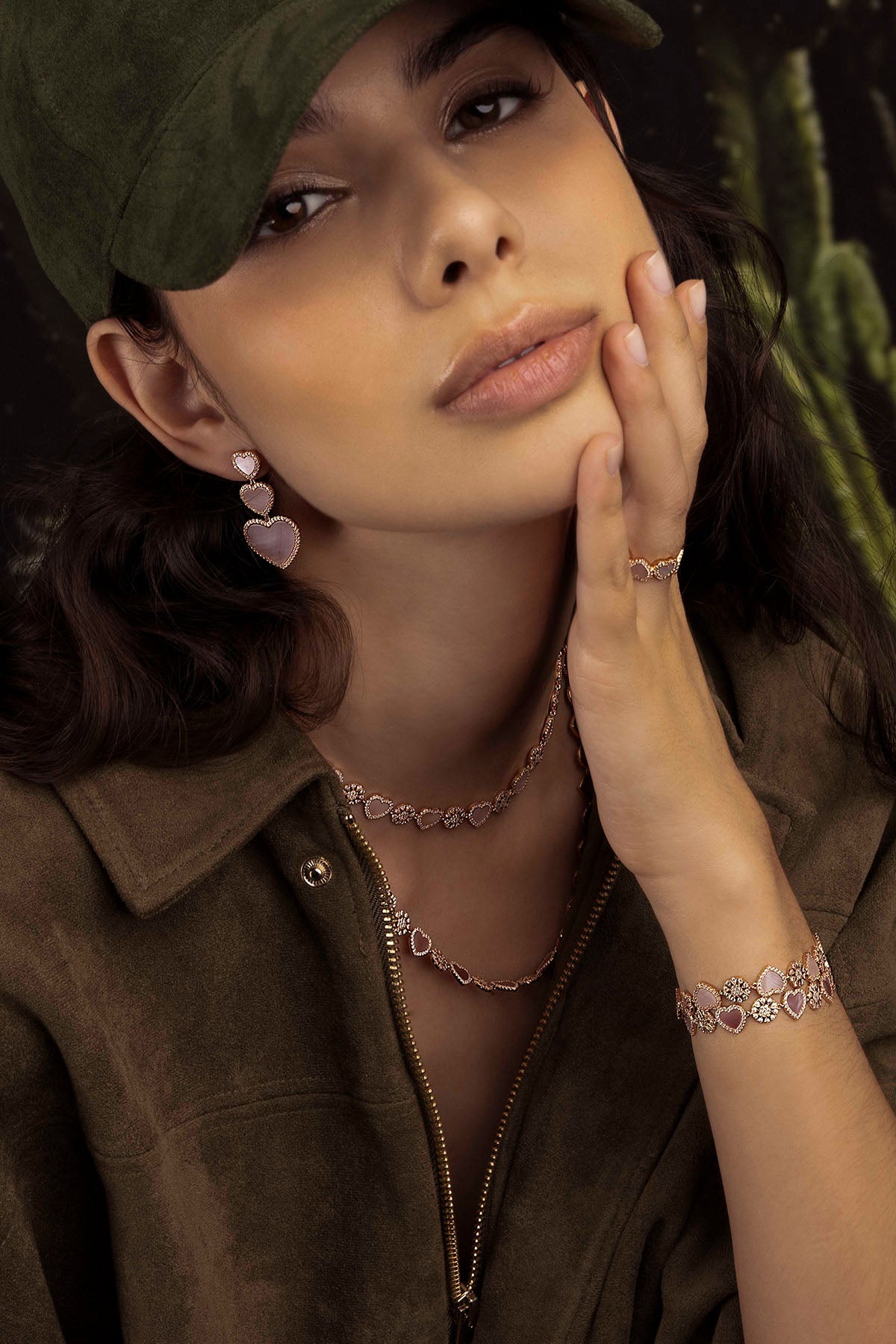 Woman wearing jewelry with a green hat and brown shirt