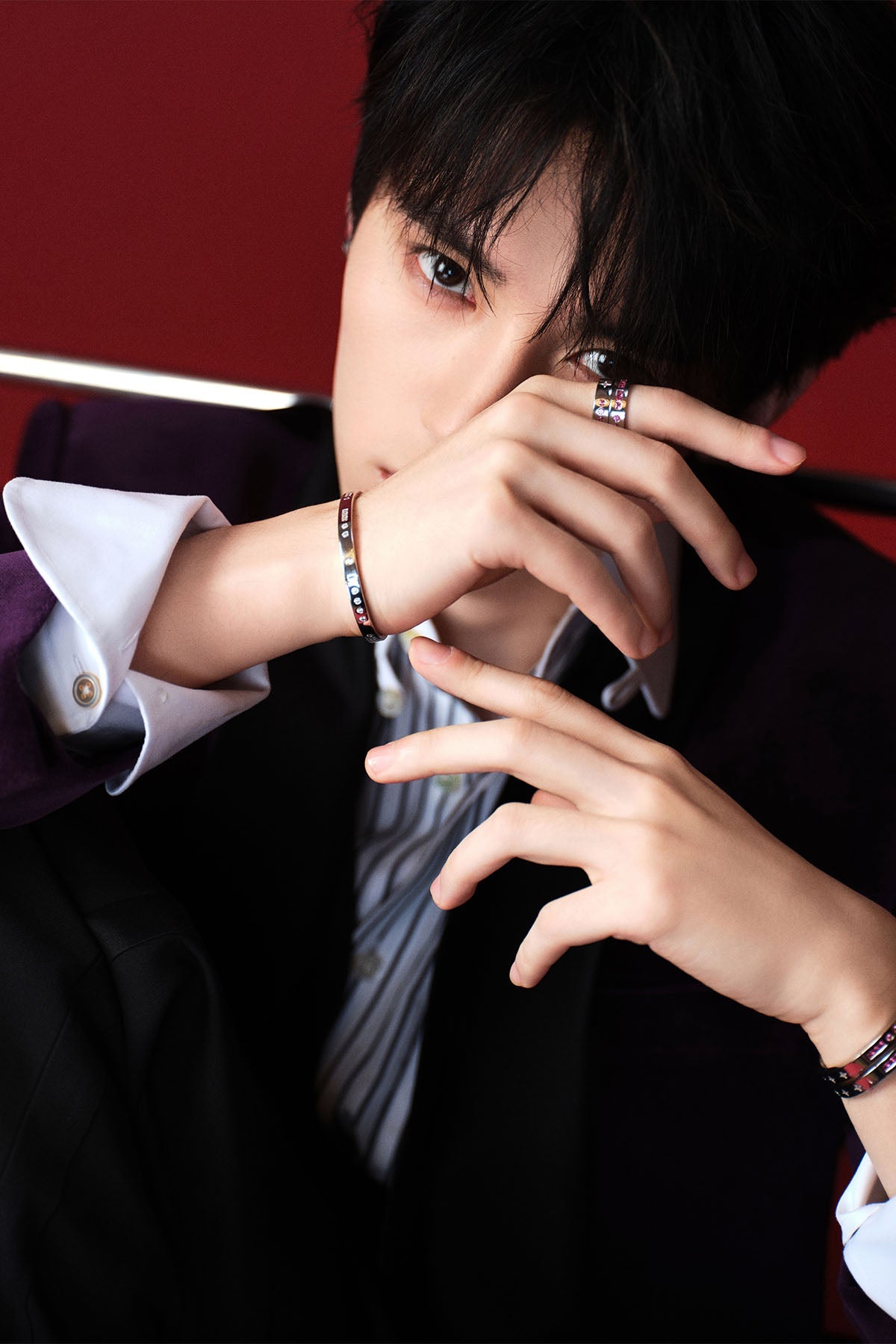 Model wearing bracelets and rings with a red background