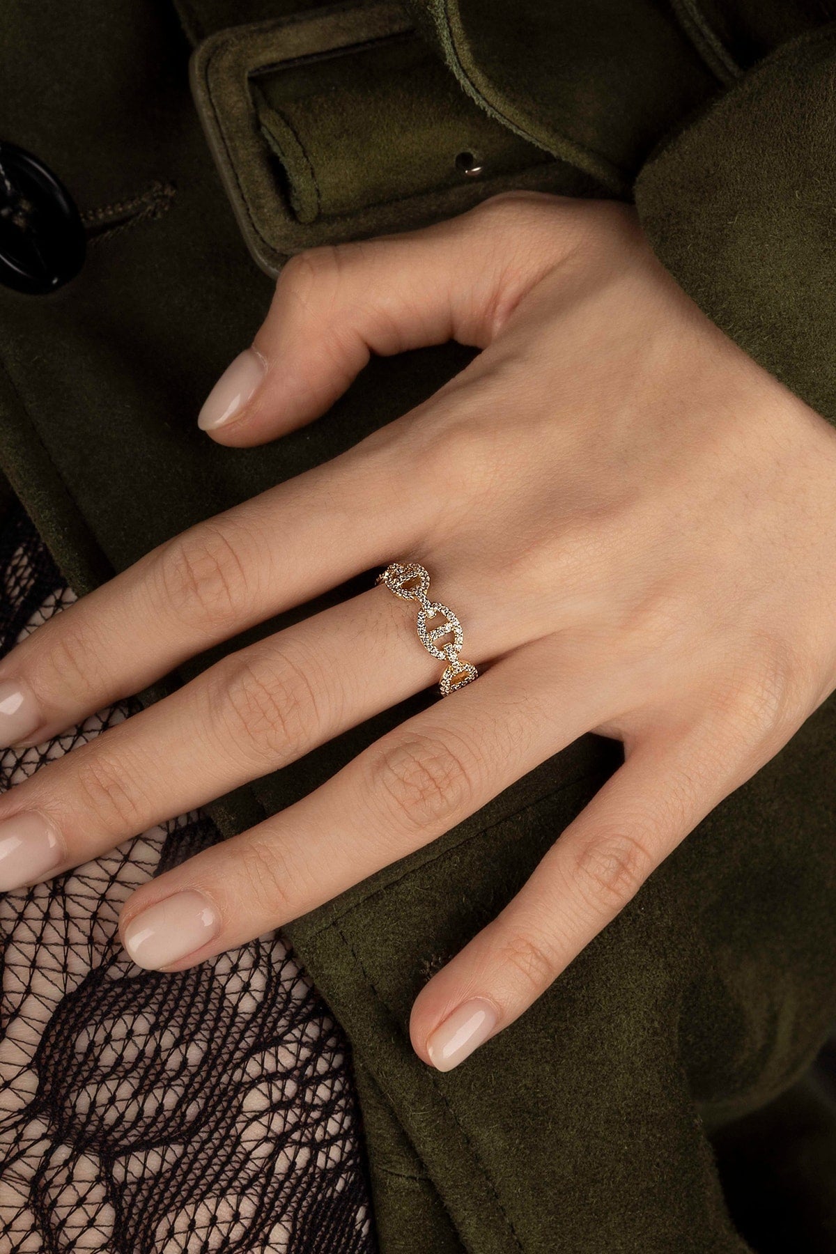 Hand wearing a diamond ring with a dark coat background