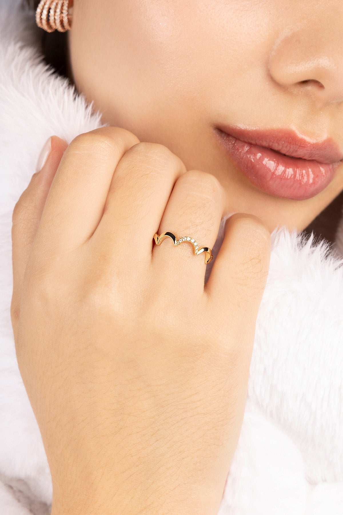 Close-up of a hand wearing a gold plated ring with a soft white background
