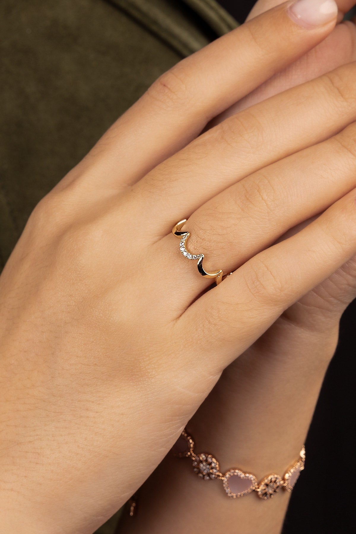 Hand wearing a gold ring on a dark background