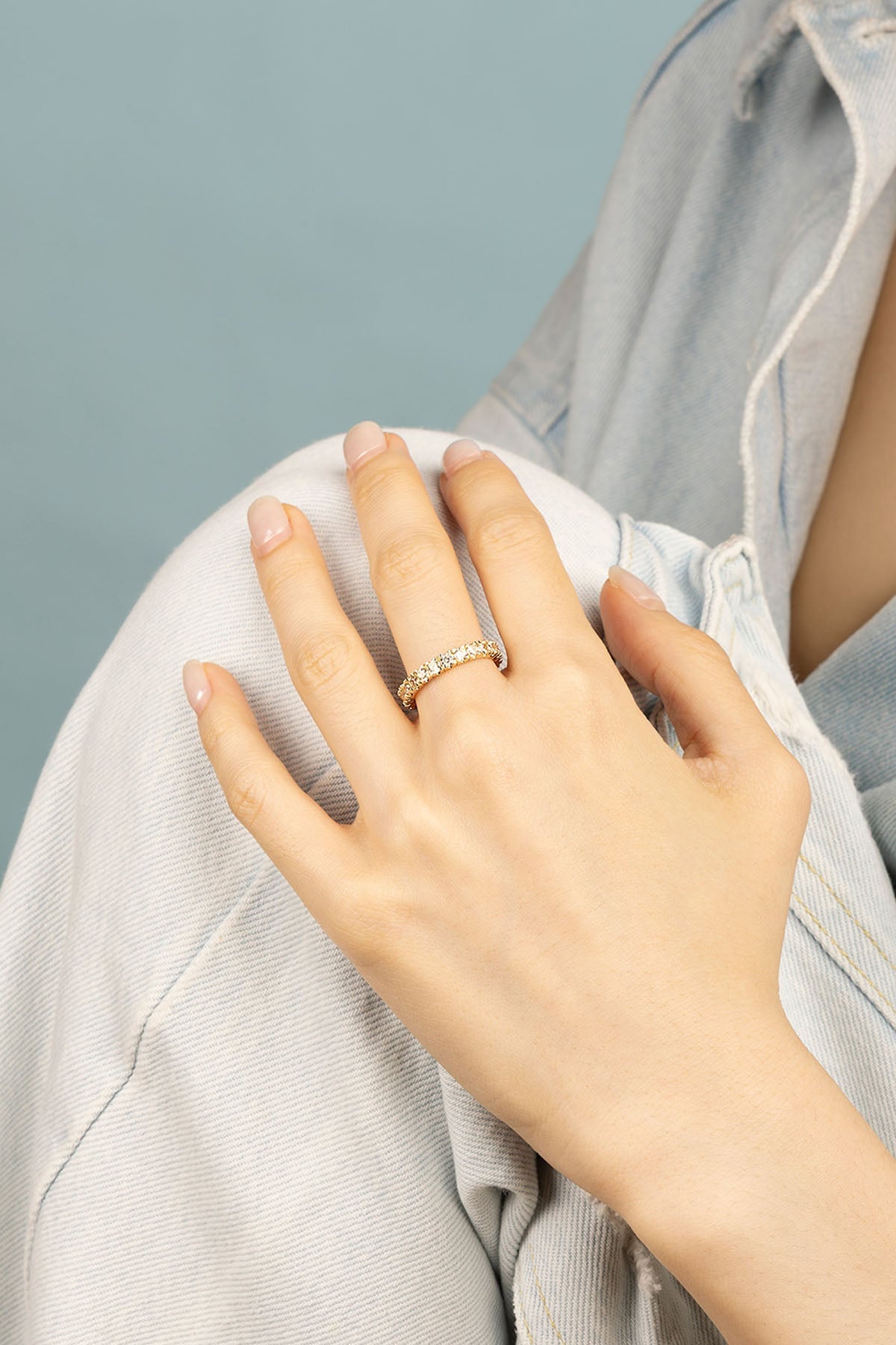 Rings APM Monaco, white pavé eternity ring worn on a finger, featuring a continuous band of small clear stones set in white metal.