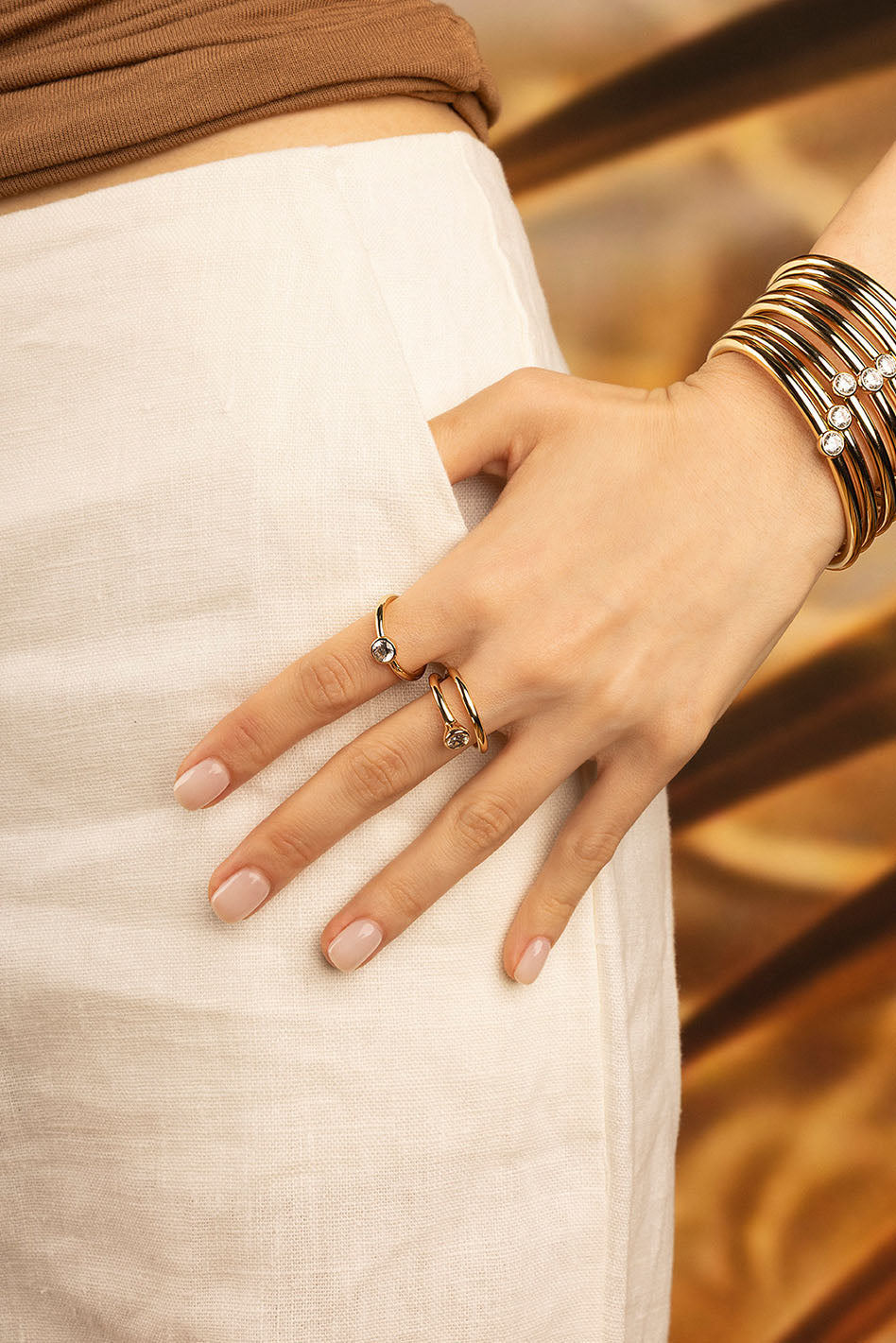 Rings APM Monaco: yellow gold stacking rings with a twisted design on a hand.