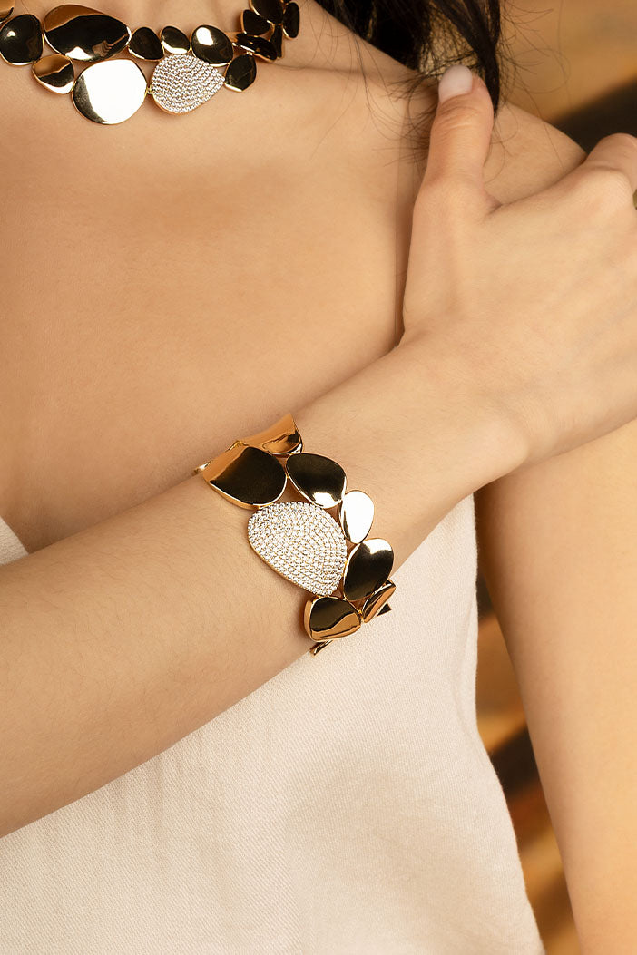 Bracelets APM Monaco: gold-plated, petal-inspired galet bangle with one petal encrusted with rhinestones.