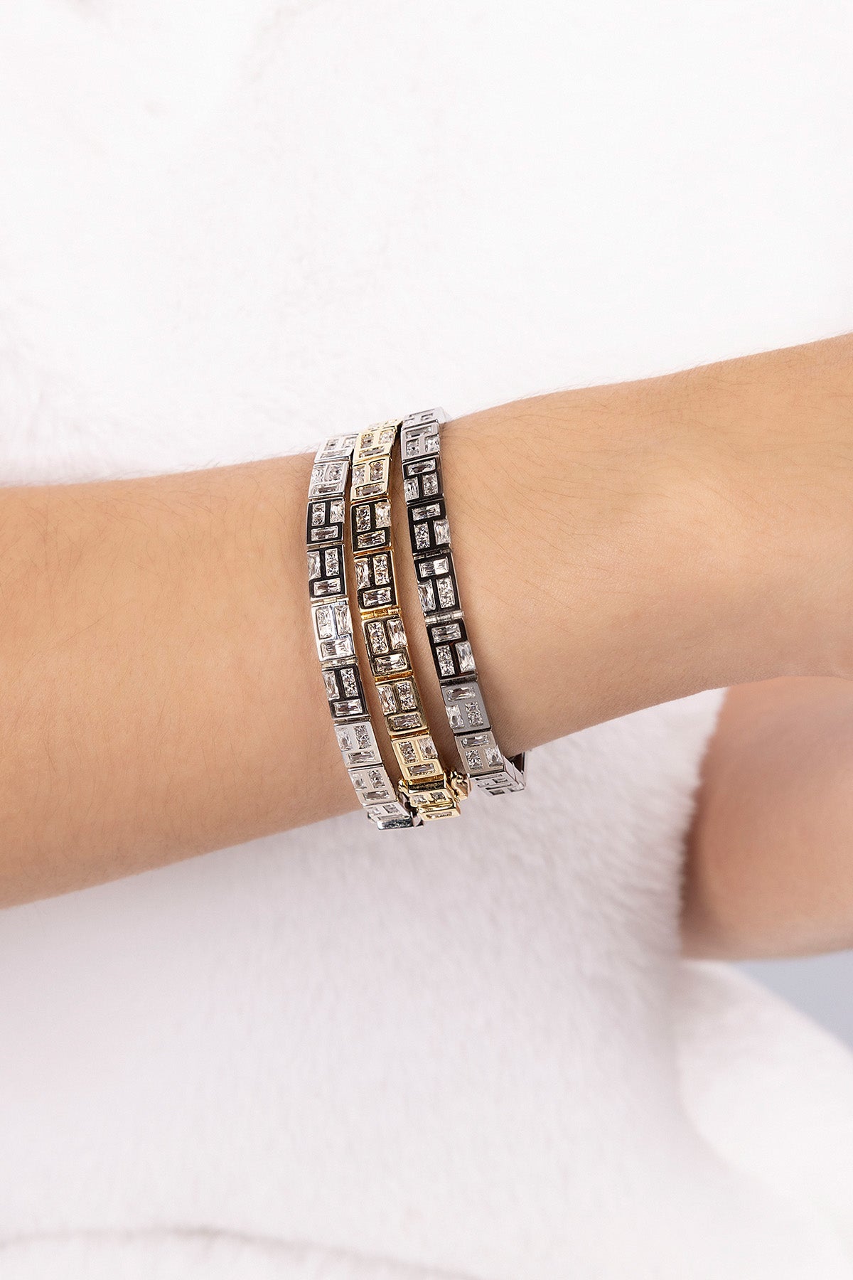 Three APM MONACO labyrinth bracelets on a wrist against a white background