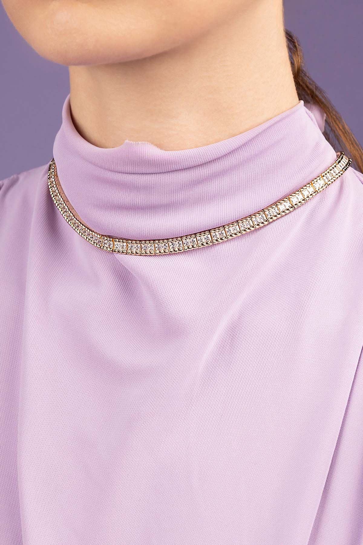 Close-up of a lavender top with a decorative neckline against a purple background
