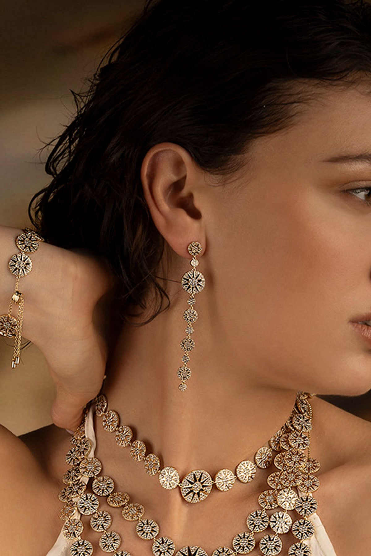 Earrings APM Monaco long soleil drop with a circular sun motif in yellow gold.